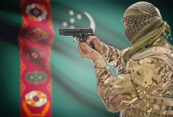 Male in muslim keffiyeh with gun in hand and national flag on background - Turkmenistan — Stockfoto