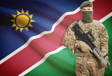 Soldier holding machine gun with flag on background series - Namibia