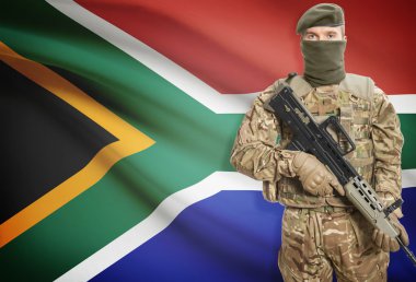Soldier holding machine gun with flag on background series - South Africa