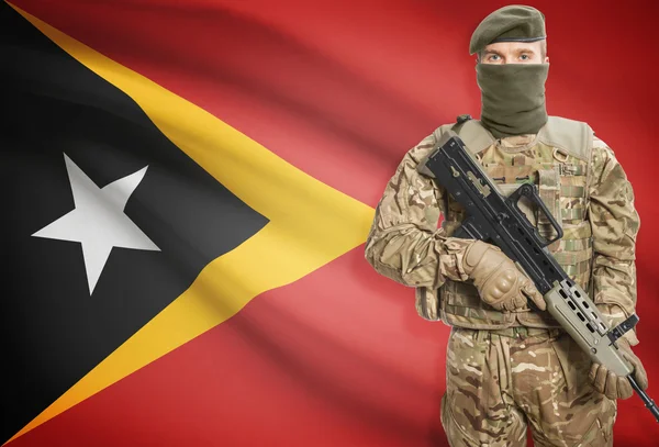 Soldier holding machine gun with flag on background series - East Timor — Stok Foto