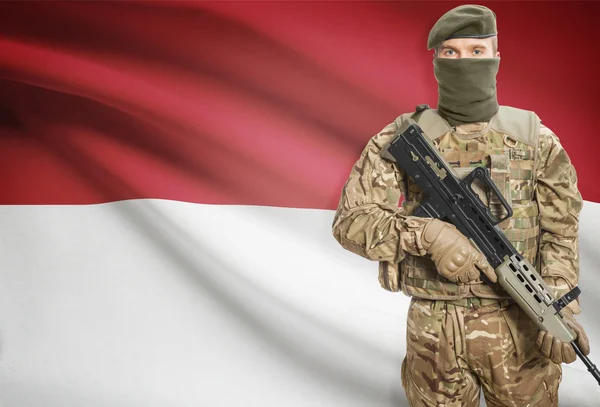 Soldier holding machine gun with flag on background series - Indonesia — Stok Foto