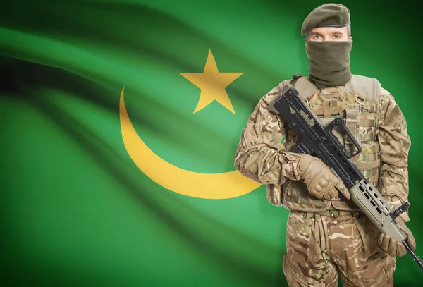 Soldier holding machine gun with flag on background series - Mauritania – stockfoto