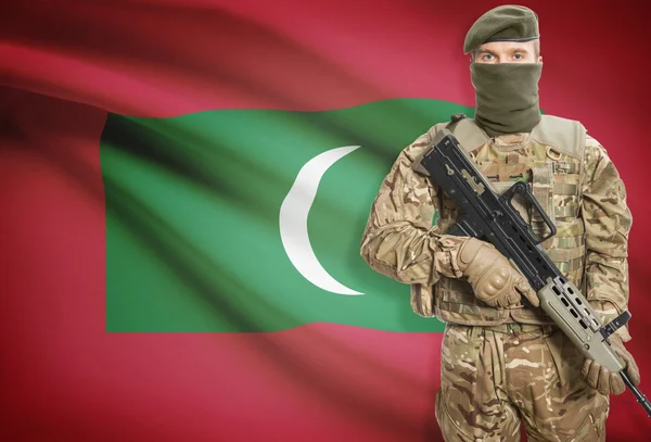 Soldier holding machine gun with flag on background series - Maldives — Stock Photo, Image