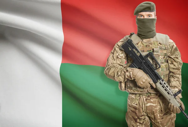 Soldier holding machine gun with flag on background series - Madagascar — Stock Fotó