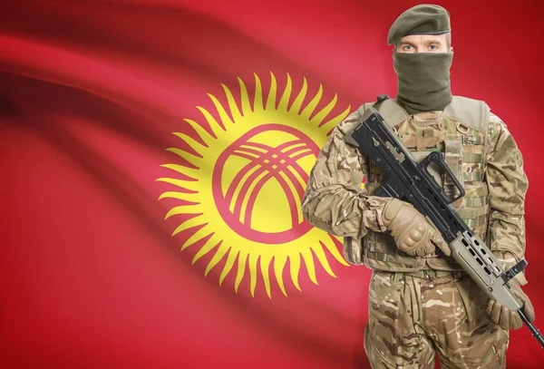 Soldier holding machine gun with flag on background series - Kyrgyzstan — Zdjęcie stockowe