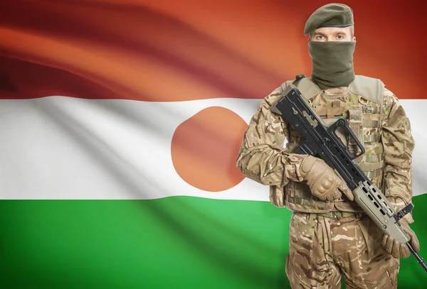 Soldier holding machine gun with flag on background series - Niger — стокове фото