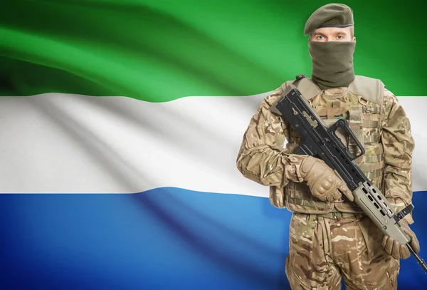 Soldier holding machine gun with flag on background series - Sierra Leone — стокове фото