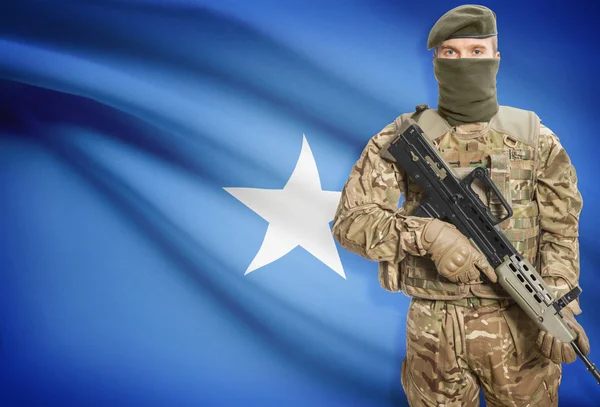 Soldier holding machine gun with flag on background series - Somalia —  Fotos de Stock