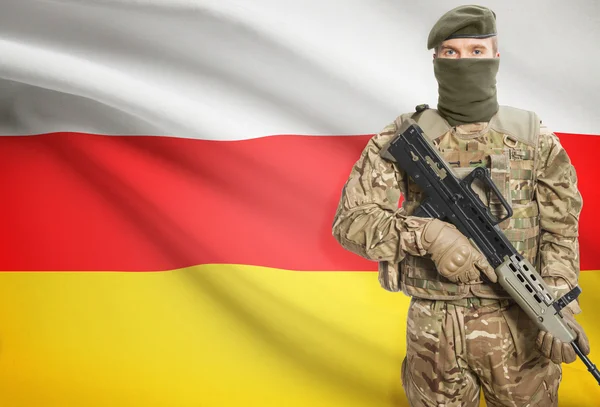 Soldier holding machine gun with flag on background series - South Ossetia — стокове фото