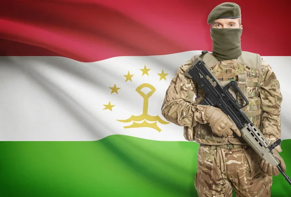 Soldier holding machine gun with flag on background series - Tajikistan – stockfoto