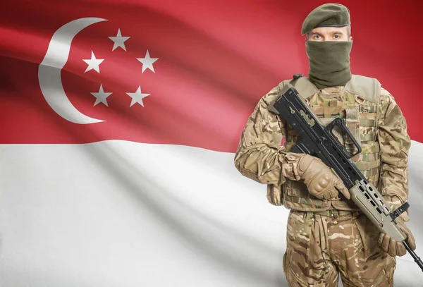Soldier holding machine gun with flag on background series - Singapore — Stock Photo, Image