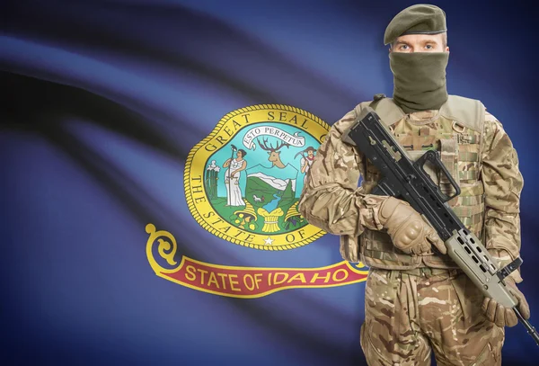 Soldier holding machine gun with USA state flag on background series - Idaho — Stock Photo, Image