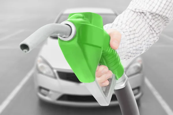 Pistola di un pompa di benzina di colore verde in mano con automobile su priorità bassa — Foto Stock