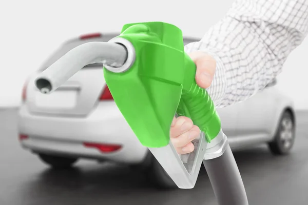 Verde fucile a pompa carburante a disposizione con auto su priorità bassa — Foto Stock