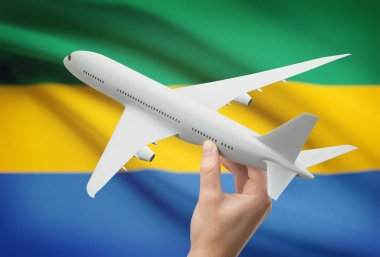 Airplane in hand with flag on background - Gabon clipart