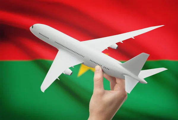 Flugzeug in der Hand mit Flagge auf Hintergrund - Burkina Faso — Stockfoto