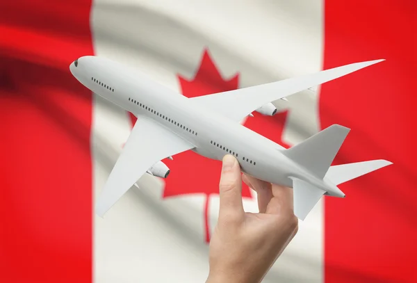 Самолет в руку с флагом на фоне - Канада — стоковое фото