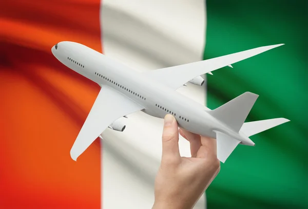 Flugzeug in der Hand mit Flagge auf Hintergrund - Elfenbeinküste — Stockfoto