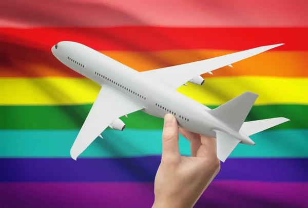 Avión en la mano con la bandera en el fondo - personas Lgbt — Foto de Stock