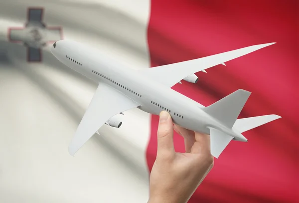 Airplane in hand with flag on background - Malta — Stock Photo, Image