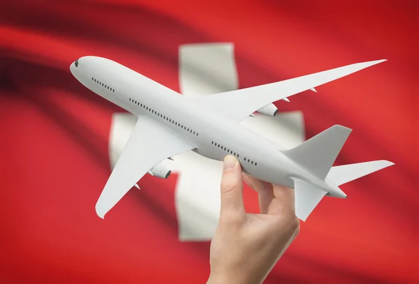Самолет в руку с флагом на фоне - Швейцария — стоковое фото