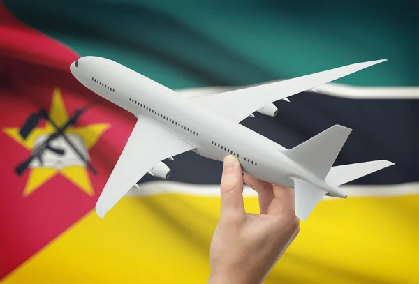 Airplane in hand with flag on background - Mozambique — Stock Photo, Image