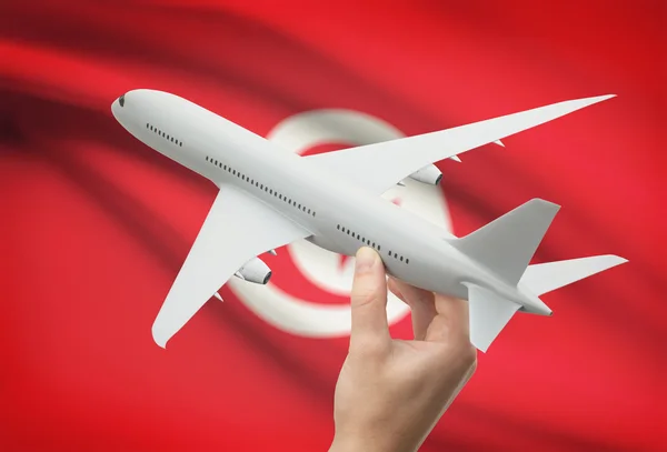 Samolot w rękę z flagi na tle - Tunezja — Zdjęcie stockowe