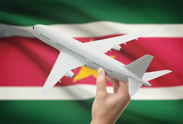 Vliegtuig in hand met vlag op achtergrond - Suriname — Stockfoto