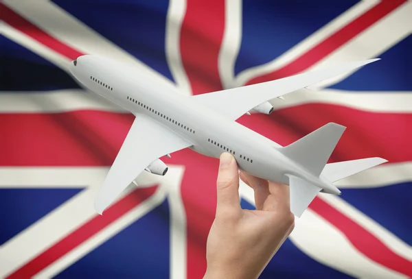 Flygplan i hand med flaggan på bakgrund - Storbritannien — Stockfoto