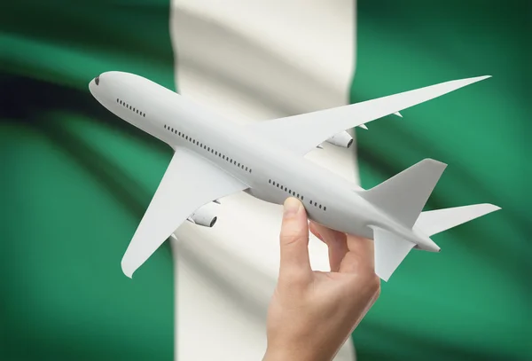 Airplane in hand with flag on background - Nigeria — Stock Photo, Image