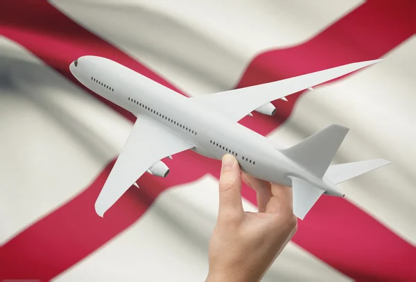 Airplane in hand with US state flag on background - Alabama — Stock Photo, Image