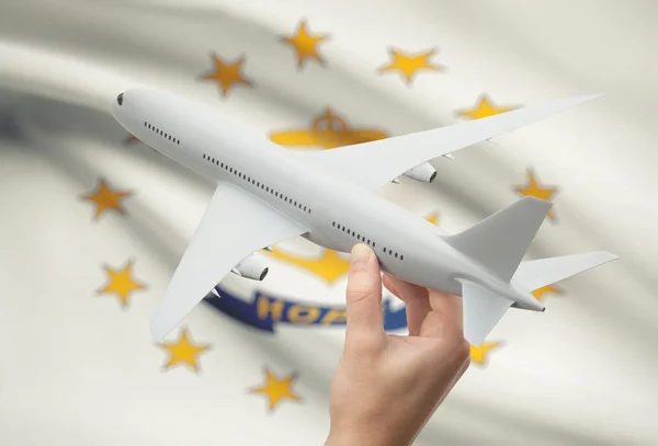 Airplane in hand with US state flag on background - Rhode Island — Stockfoto