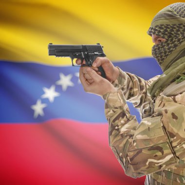 Male with gun in hands and national flag on background - Venezuela