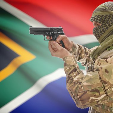 Male with gun in hands and national flag on background - South Africa
