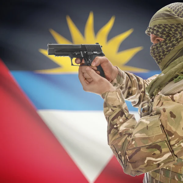 Mâle avec des armes à feu dans les mains et le drapeau national sur fond - Antigua et Barbuda — Photo