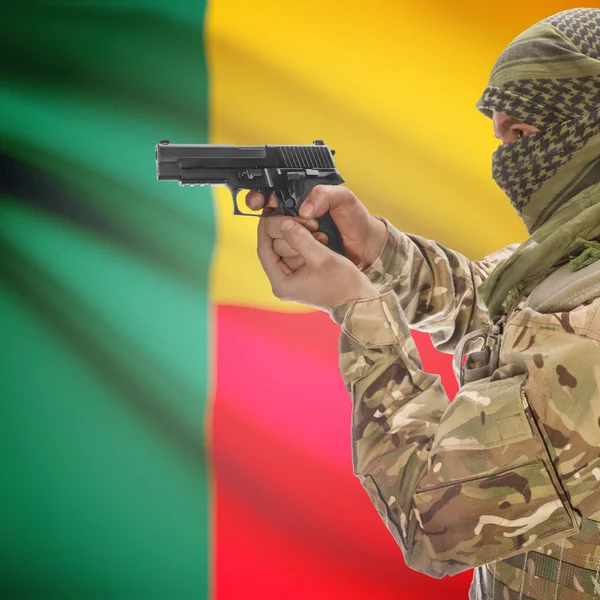 Male with gun in hands and national flag on background - Benin — Stock Photo, Image