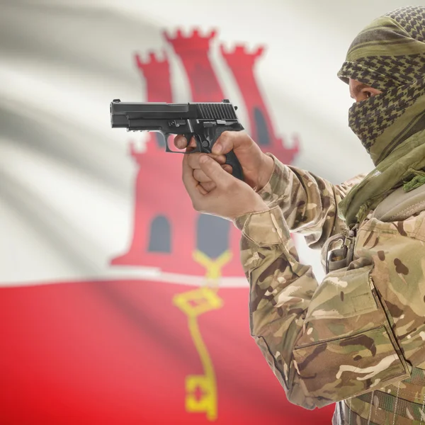 Férfi pisztollyal a kezében és a háttér - Gibraltár zászlaja — Stock Fotó