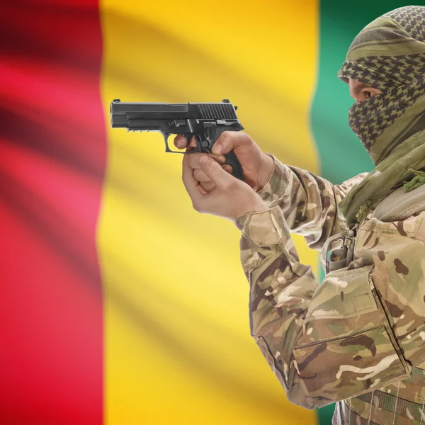 Male with gun in hands and national flag on background - Guinea — Stock Photo, Image