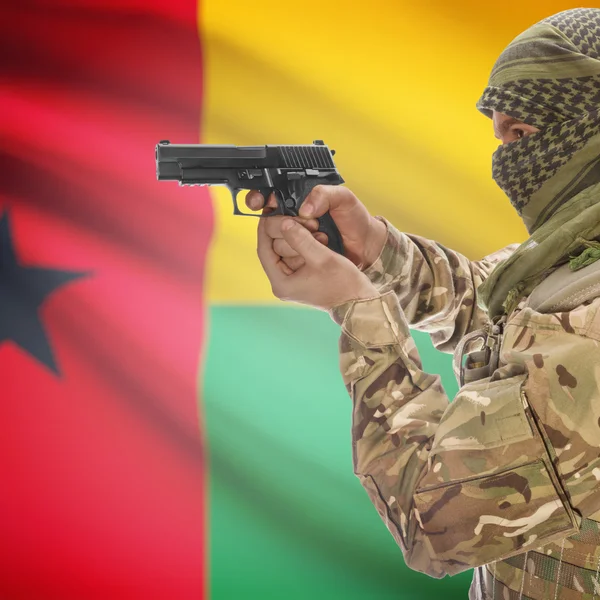 Férfi pisztollyal a kezében, és háttér - Bissau-Guinea zászlaja — Stock Fotó