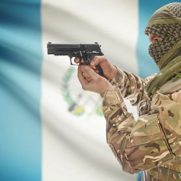 Mâle avec des armes à feu dans les mains et le drapeau national sur fond - Guatemala — Photo