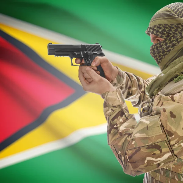 Male with gun in hands and national flag on background - Guyana — Stock Photo, Image