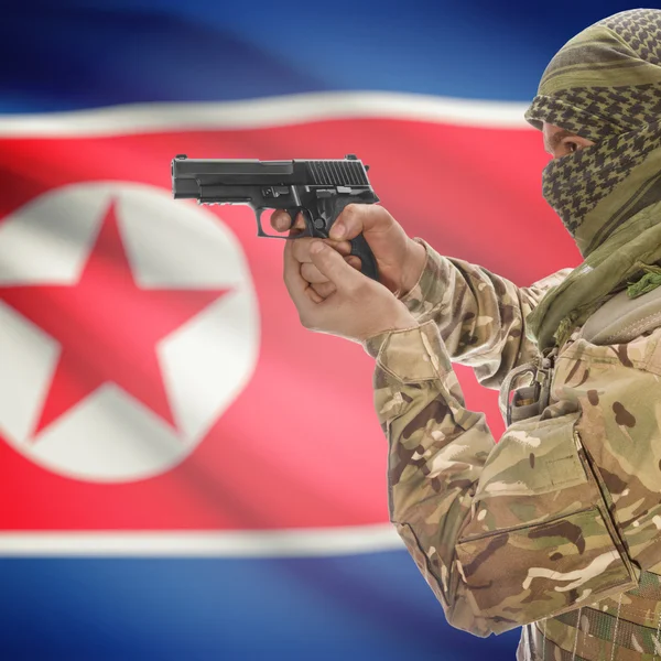 Homem com arma em mãos e a bandeira nacional no plano de fundo - Coreia do Norte — Fotografia de Stock