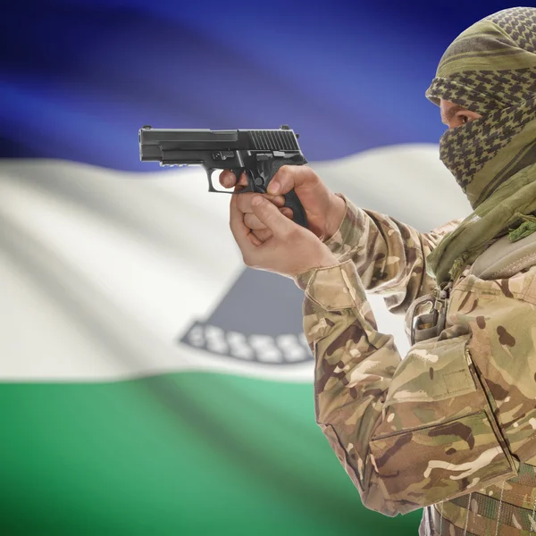 Male with gun in hands and national flag on background - Lesotho — Stok Foto