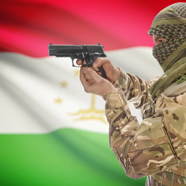 Male with gun in hands and national flag on background - Tajikistan — Stok Foto