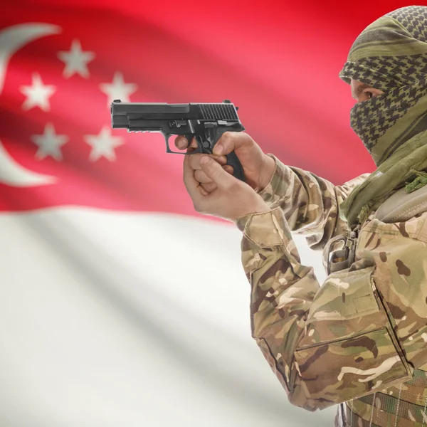 Male with gun in hands and national flag on background - Singapore — Stock Photo, Image