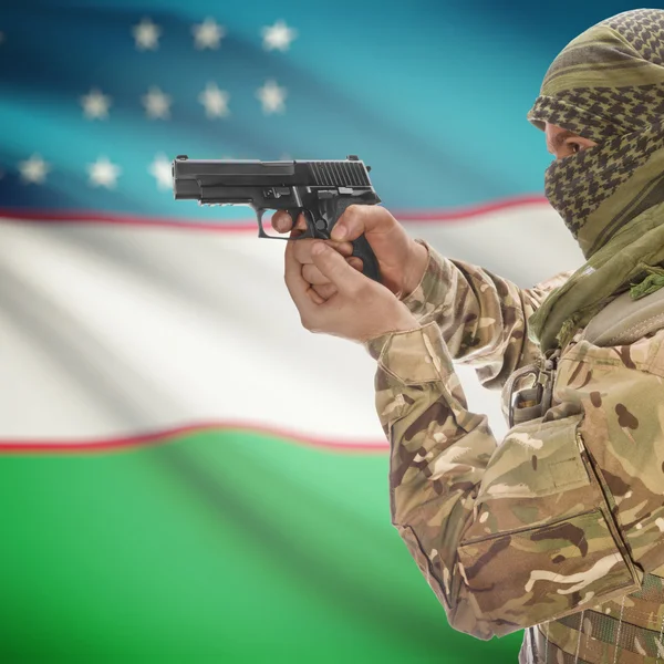 Male with gun in hands and national flag on background - Uzbekistan — Stok Foto