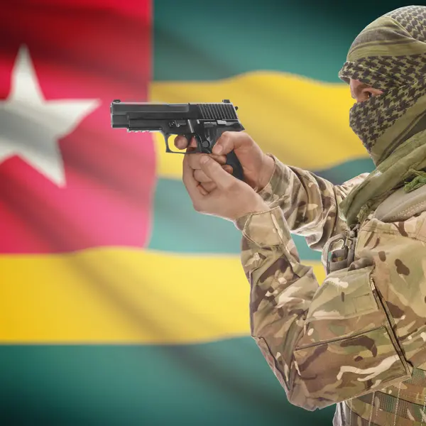 Male with gun in hands and national flag on background - Togo — ストック写真