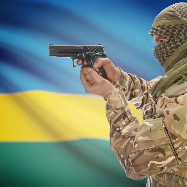 Male with gun in hands and national flag on background - Rwanda — Stock Photo, Image