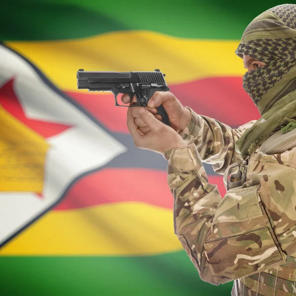 Mann mit einer Pistole in der Hand und Nationalflagge auf den Hintergrund - Simbabwe — Stockfoto