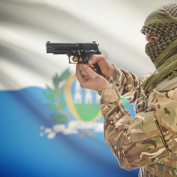 Homme avec un pistolet dans les mains et le drapeau national sur le fond - Saint-Marin — Photo